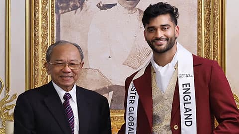 Baltej Tattla wearing a sash that reads Mr England on it. He is smiling and shaking hands with someone.